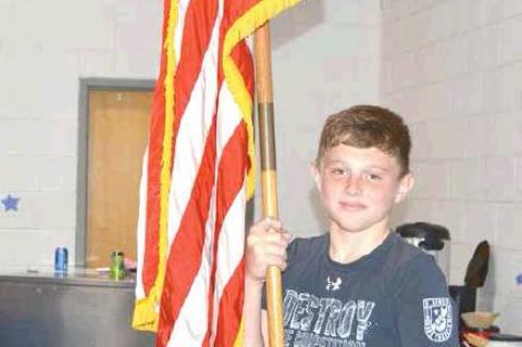 Sixth grader Gage Rice posts the American flag.